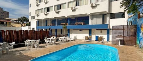 Una piscina al aire libre, sillones reclinables de piscina