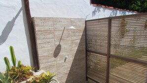 Un petit espace extérieur doté d’une terrasse en bois, d’un mur carrelé et d’une clôture en métal.