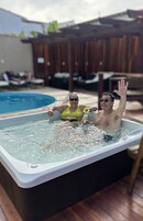Un jacuzzi con dos personas, una de ellas levantando la mano.