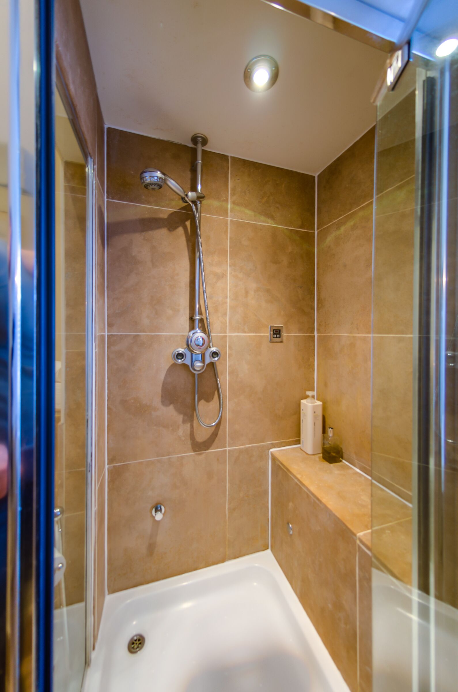 A modern shower area with a handheld showerhead, a built-in bathtub, and a glass shower enclosure.