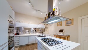 A modern kitchen with white cabinets, a gas stove, and a built-in oven. - 5* Luxury Suite Central Edinburgh stunning views of Edinburgh Castle! (Edinburgh)