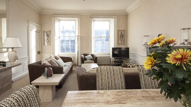 A living room with a sofa set, a coffee table, a TV, and a large window. - 5* Luxury Suite Central Edinburgh stunning views of Edinburgh Castle! (Edinburgh)