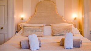 A neatly made bed with two pillows, two rolled towels, and a headboard with wall-mounted lights. - 5* Luxury Suite Central Edinburgh stunning views of Edinburgh Castle! (Edinburgh)