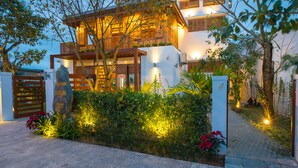 Une maison moderne à deux étages, dotée d’une façade en bois, d’une entrée bien éclairée et d’une allée pavée.
