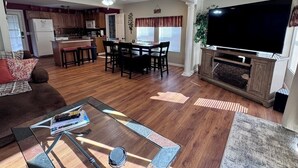 A spacious living room with a glass coffee table, a TV, and a fireplace.