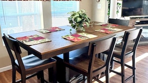 A dining area with a wooden table, four chairs, and a potted plant.