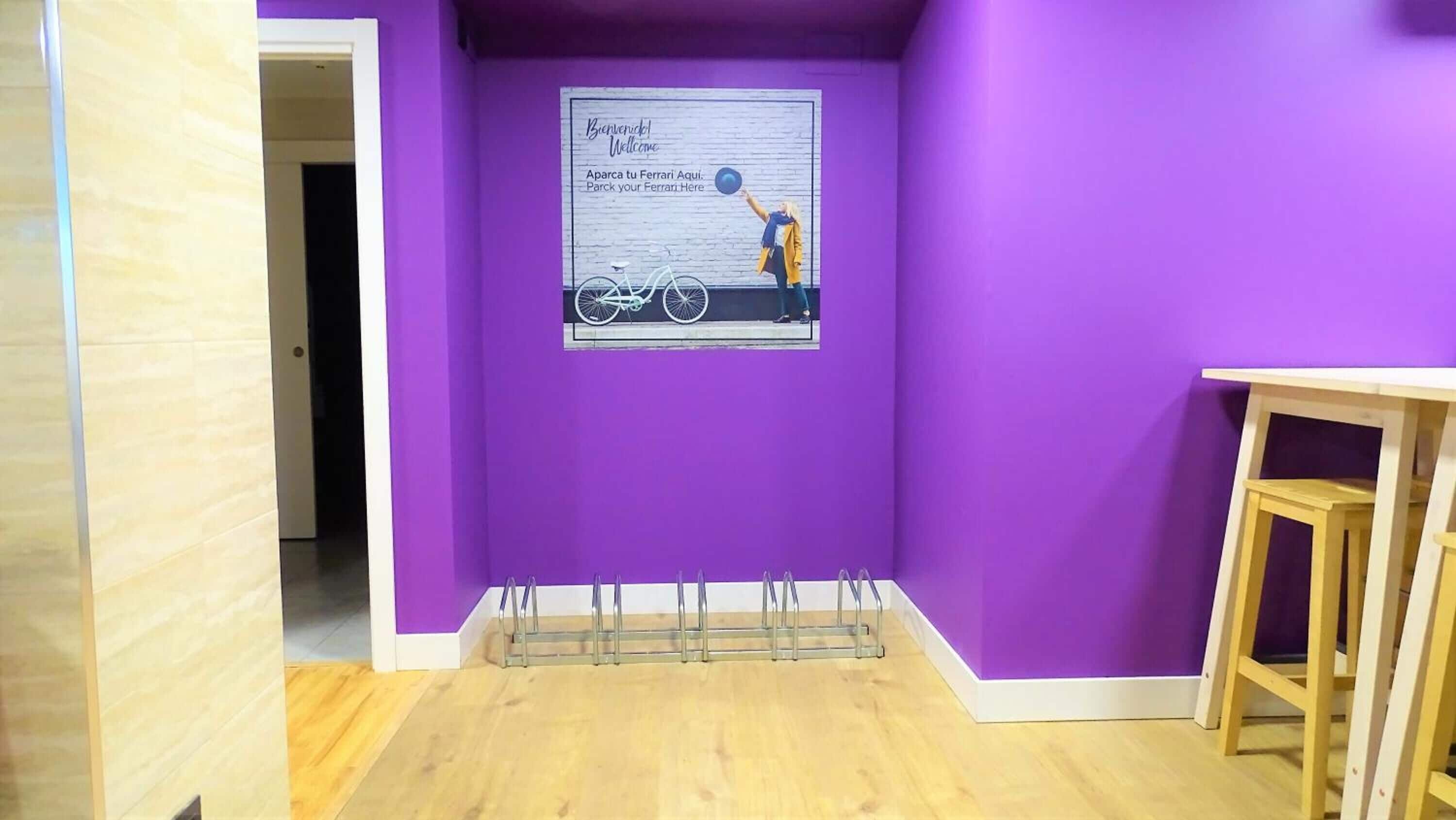 A room with purple walls, a wooden floor, and a sign on the wall.