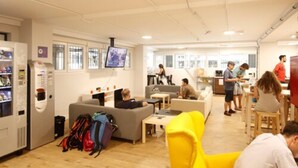 Un espace de détente moderne, doté de sièges, d’un distributeur automatique et d’un écran de télévision.