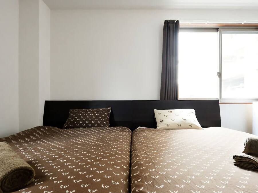 Une chambre d’hôtel avec un lit double, deux oreillers, une fenêtre avec des rideaux et une tête de lit.