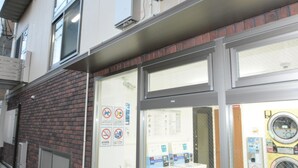 A laundromat with a brick facade, large windows, and a visible coin-operated washer and dryer. - The Wonder At Stay-Tengachaya- (Osaka)
