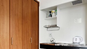 A kitchen with a wooden wardrobe, white cabinets, a black countertop, a kettle, and a refrigerator. - The Wonder At Stay-Tengachaya- (Osaka)