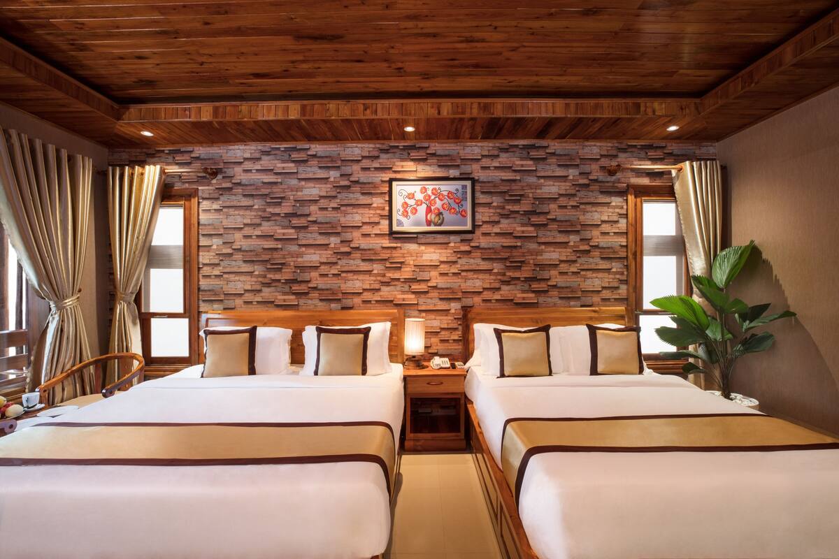Une chambre d’hôtel avec deux lits, un plafond en bois, un mur en briques et un tableau.