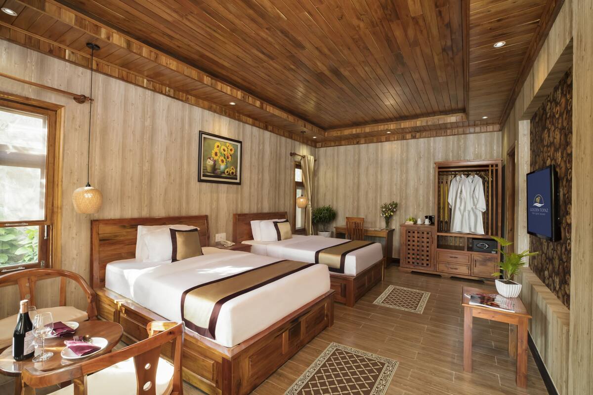 Une chambre d’hôtel avec deux lits, des meubles en bois, une télévision et un coin repas comprenant une table et des chaises.