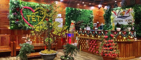 A reception area with wooden paneling, a reception desk, and various potted plants.
