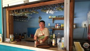 Zona de bar con mostrador, copas colgadas y diversos botellas y recipientes.