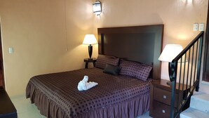 Una cama individual con una colcha estampada, una almohada, una lámpara de noche y una toalla blanca sobre la cama.