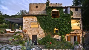 Un edificio de piedra con muros cubiertos de hiedra, una puerta de madera y una ventana pequeña.