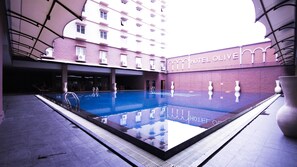 Un hotel con piscina, fachada de ladrillo y un letrero que dice "HOTEL OLIVE".