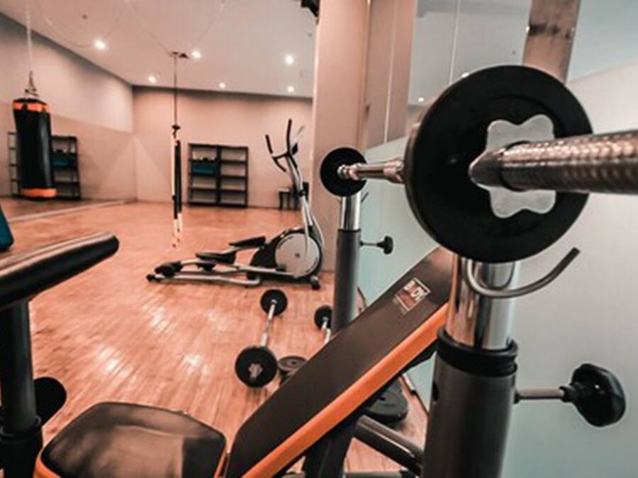 Un gimnasio con equipo de levantamiento de pesas, una banca y máquinas de cardio.