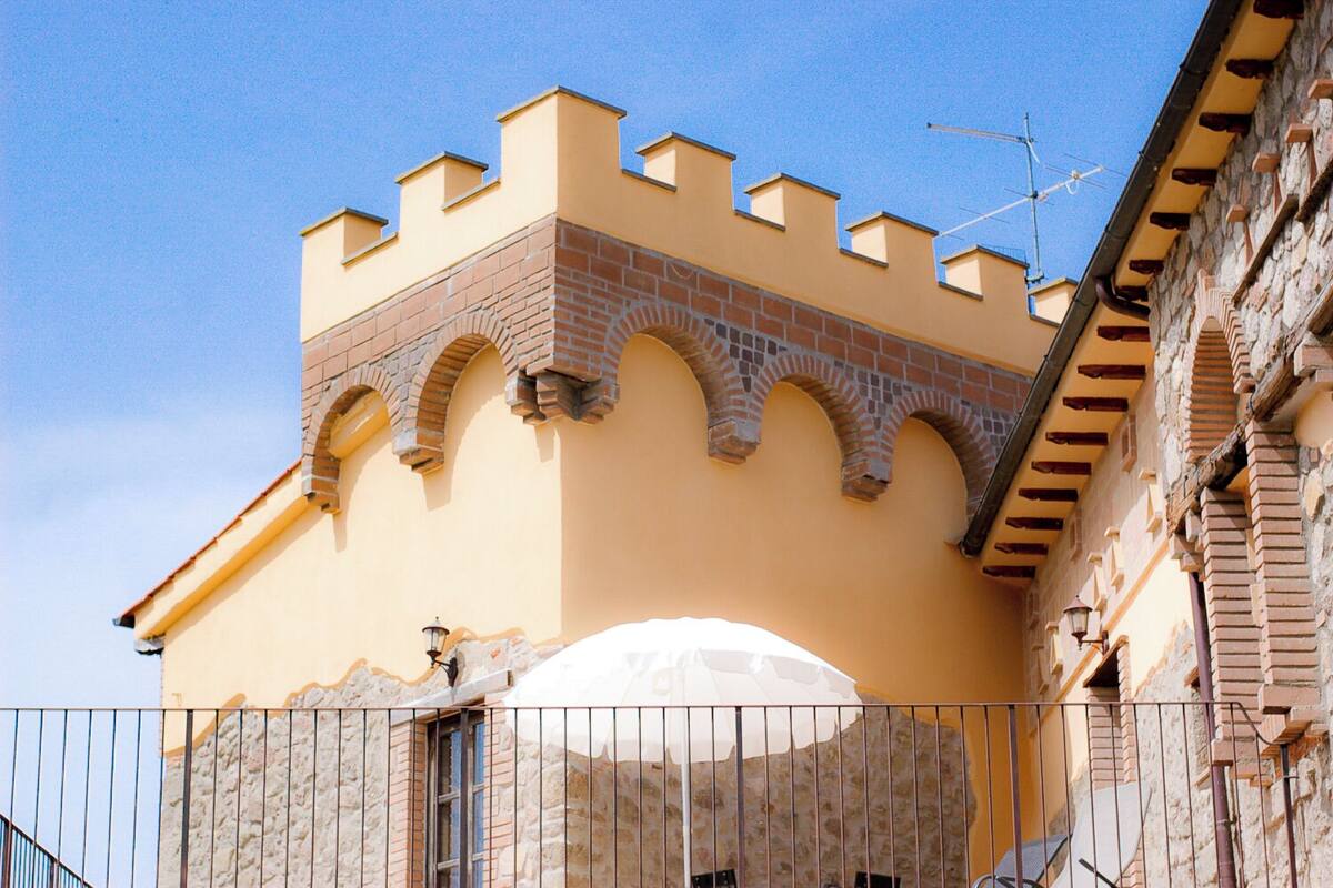 Un edificio con fachada amarilla, arcos de ladrillo y un paraguas blanco.