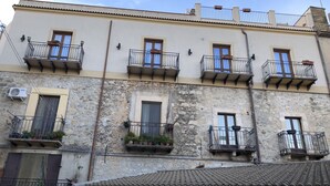 A multi-story building with balconies, stone walls, and tiled roofs. - B&B Sotto le Stelle (Caltabellotta)