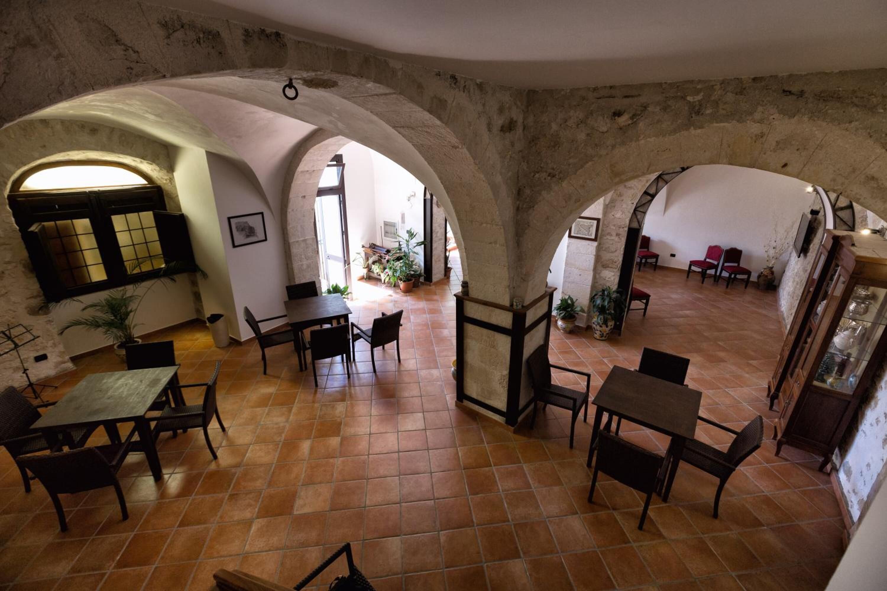 A spacious interior with high ceilings and arched stone walls, featuring multiple seating areas with tables and chairs.