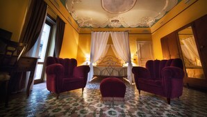 A room with a bed, two red armchairs, a wooden chair, and a mirror. - B&B Sotto le Stelle (Caltabellotta)