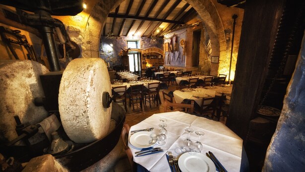 A rustic dining area with stone walls, wooden beams, and tables set for a meal. - B&B Sotto le Stelle (Caltabellotta)