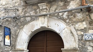 A large wooden double door with a stone archway, a mailbox, and a utility box on a stone wall. - B&B Sotto le Stelle (Caltabellotta)