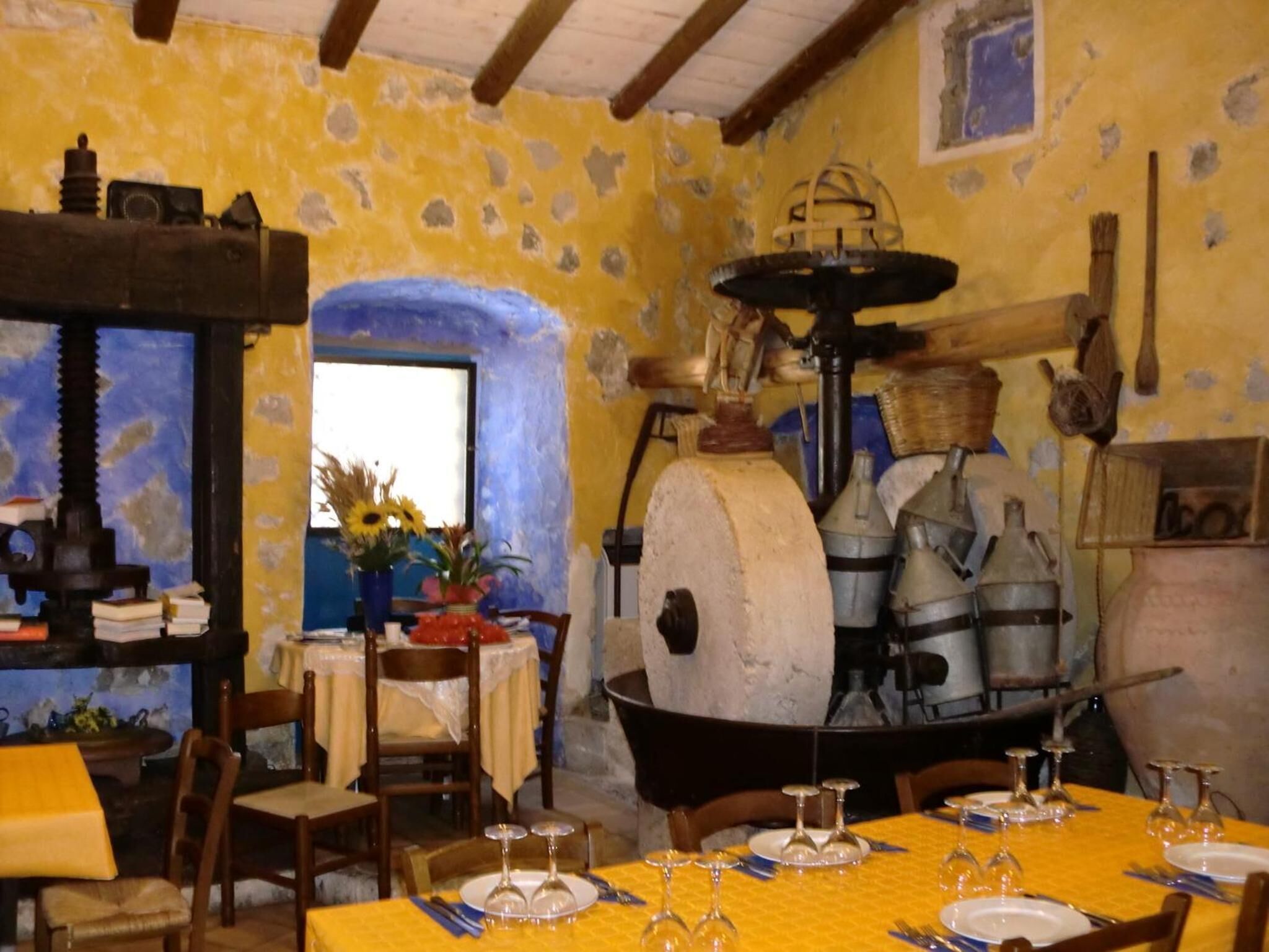 A rustic dining area with a large stone oven, wooden furniture, and a window with a view.