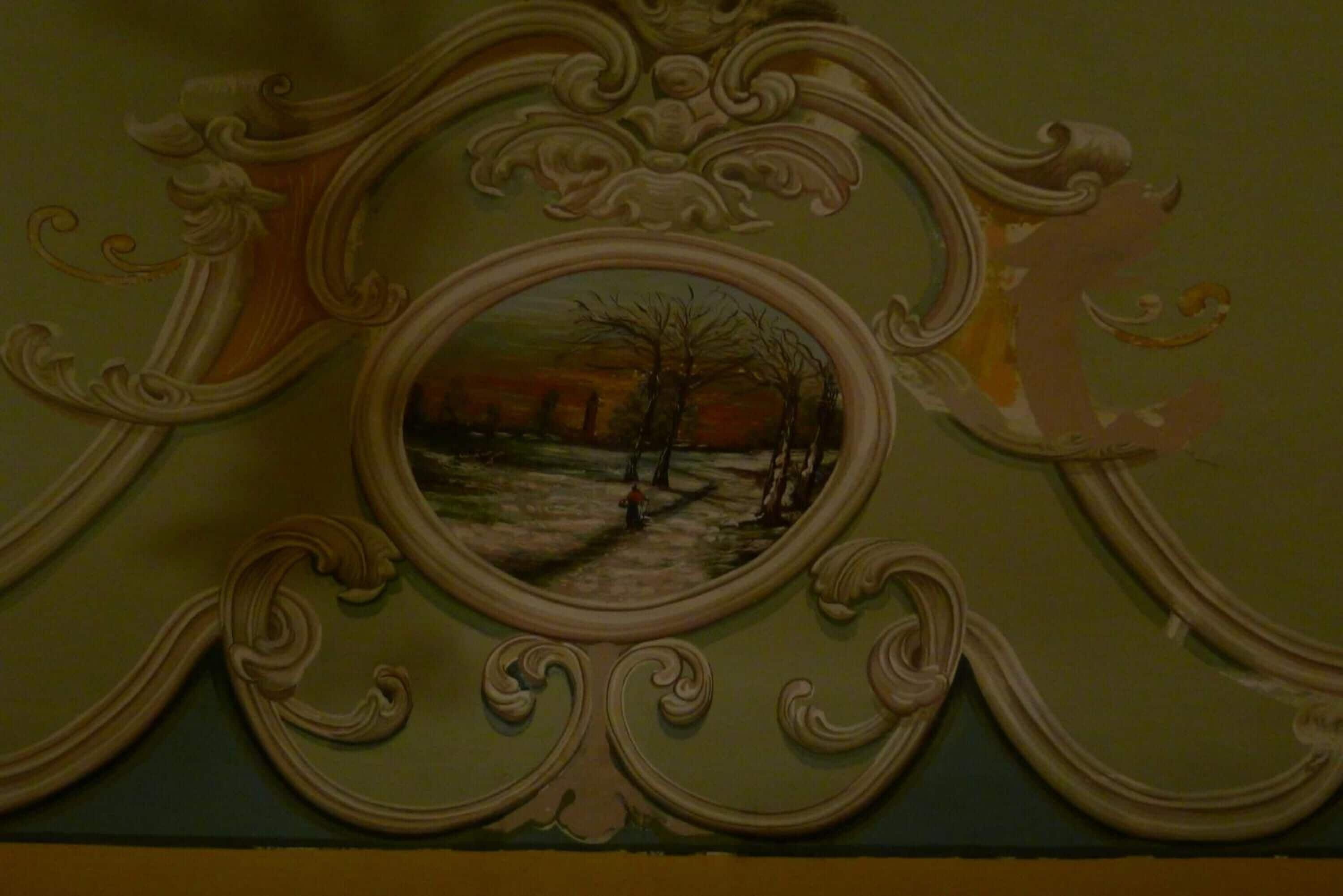 A ceiling with an ornate, circular painting surrounded by elaborate moldings.