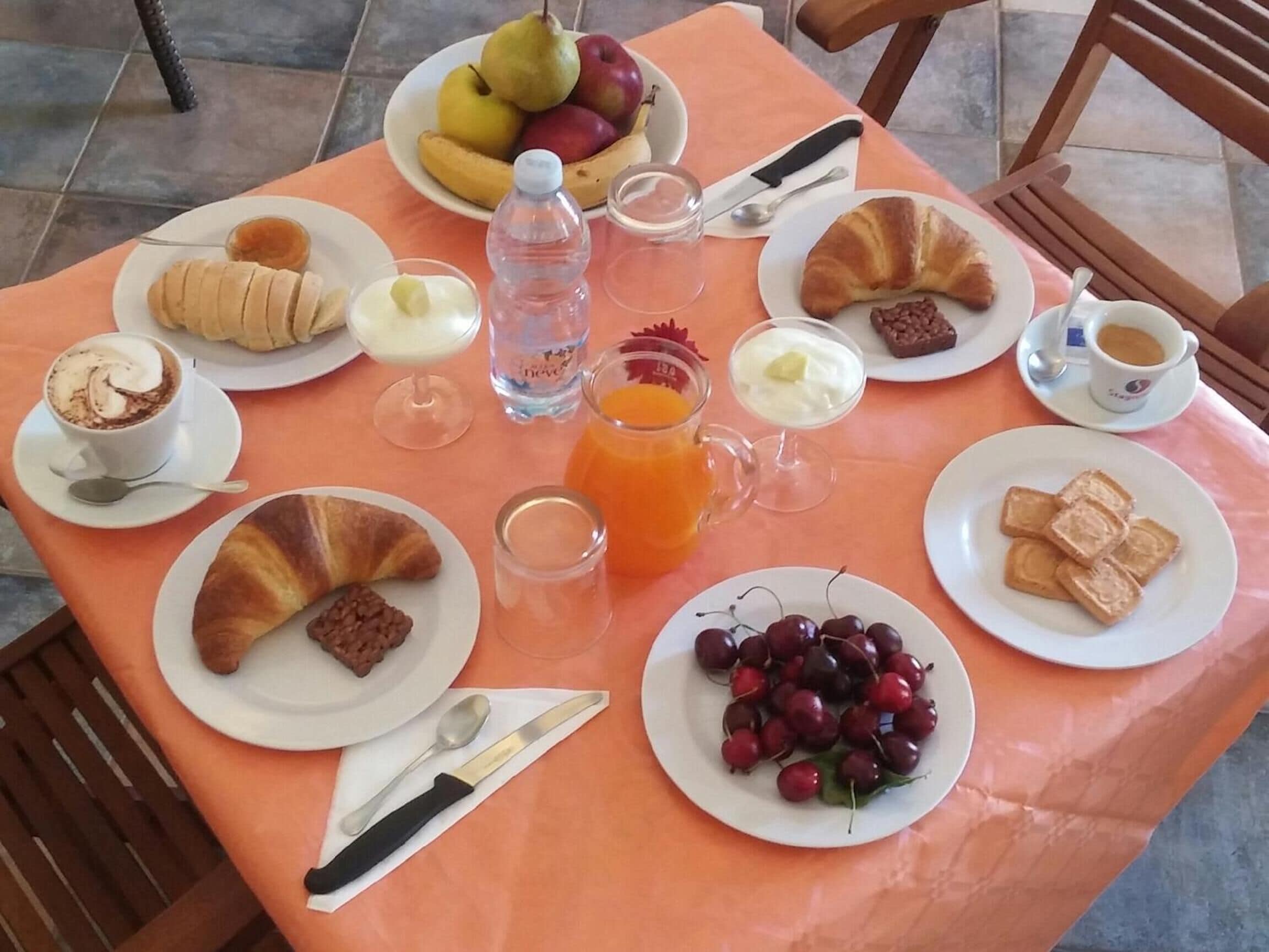 Ein Tisch mit Frühstücksleckereien, darunter Croissants, Obst und Getränke.