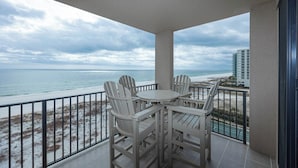 Ein Balkon mit Tisch und Stühlen mit Blick auf Strand und Meer.