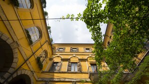A yellow building with arched doorways and windows, surrounded by greenery. - Casa Magnolia (Verona)
