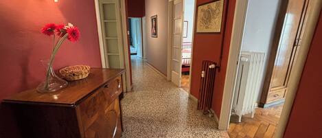 A hallway with a wooden dresser, a vase with flowers, and a framed picture on the wall.