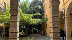 A courtyard with stone columns, a paved pathway, and a parked vehicle. - Casa Magnolia (Verona)