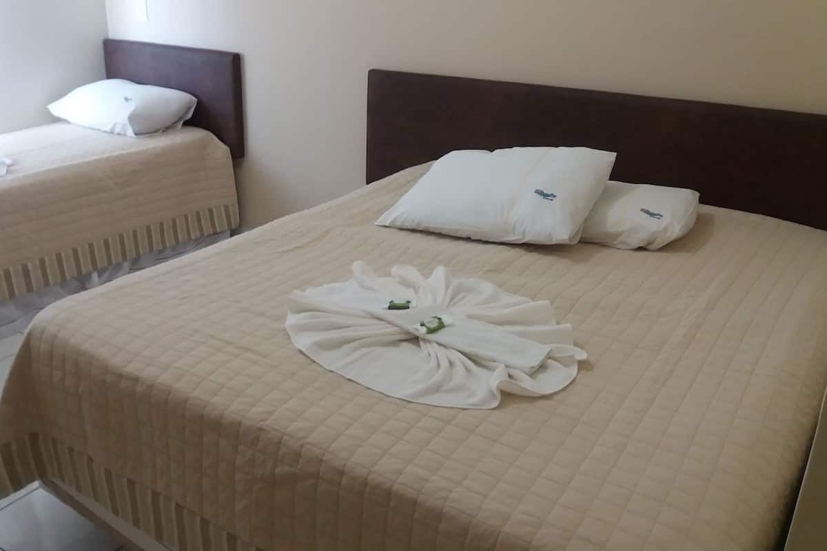 Habitación de hotel con dos camas, cada una con cabecera y almohadas.