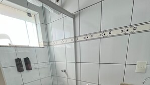 A modern bathroom with a glass shower enclosure, a white toilet, and a sink with a granite countertop. - Hotel Marcan (Sumare)