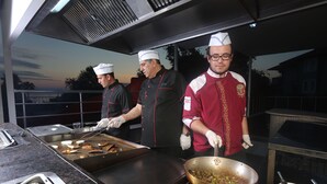 Chefs preparing food in a commercial kitchen with stainless steel surfaces and a large wok. - Mysea Hotels Incekum (Alanya)