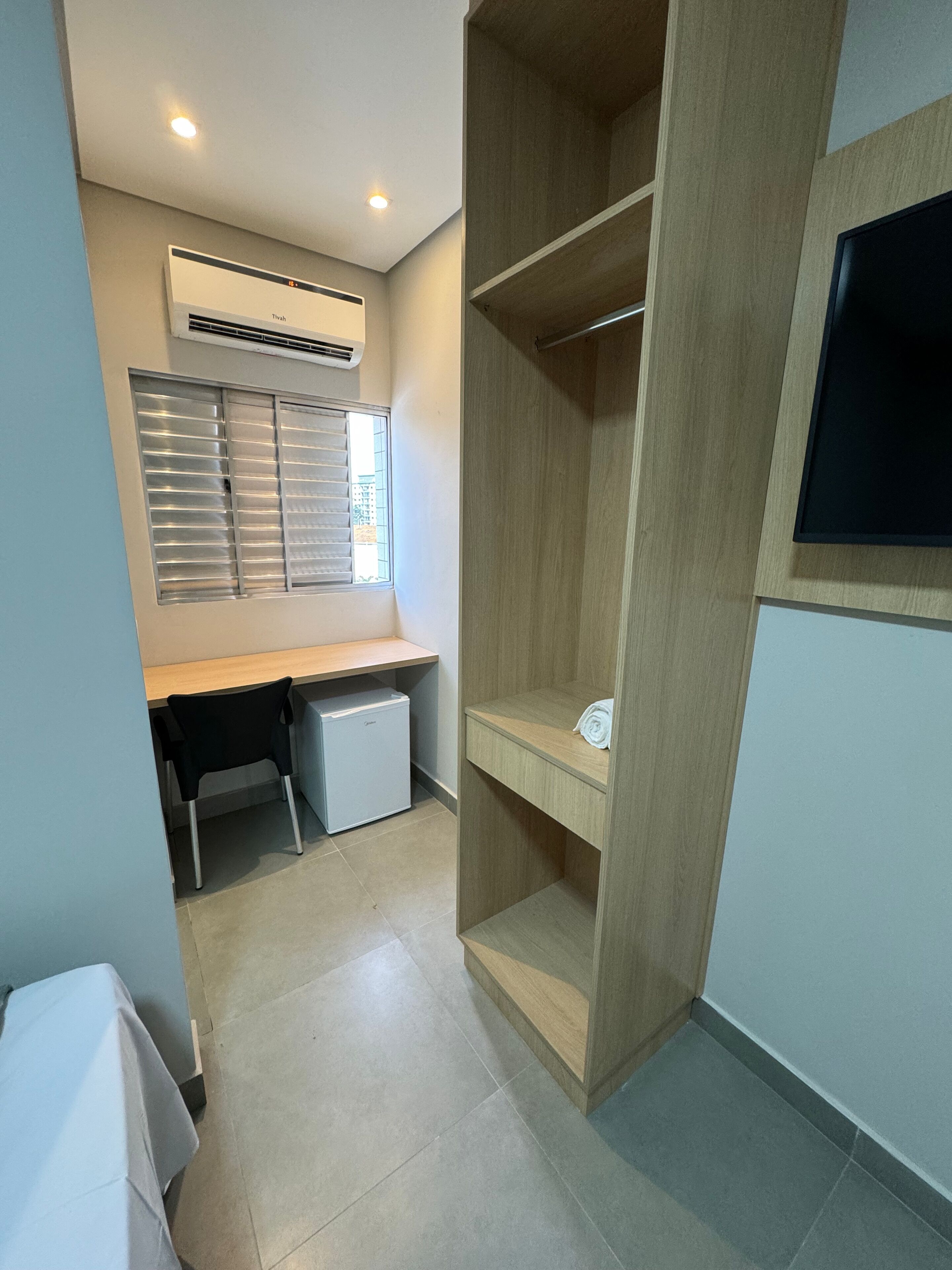 Une pièce compacte dotée d’une kitchenette, d’une armoire intégrée et d’un téléviseur à écran plat fixé au mur.