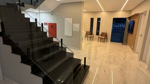 A modern interior with a glass staircase, marble flooring, and contemporary lighting.