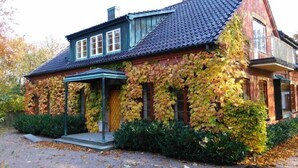 Une maison dotée d’un porche abrité, de murs recouverts de lierre et d’un toit en tuiles.