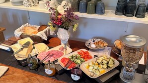 Un buffet proposant une variété de plats, notamment des viandes, des fromages, des fruits et des pâtisseries.