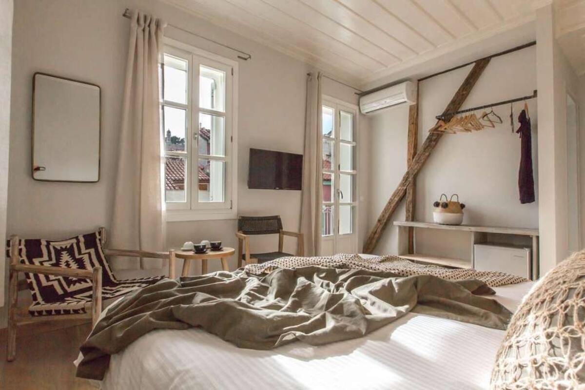 Une chambre à coucher comprenant un lit, une chaise, une petite table et un téléviseur fixé au mur.