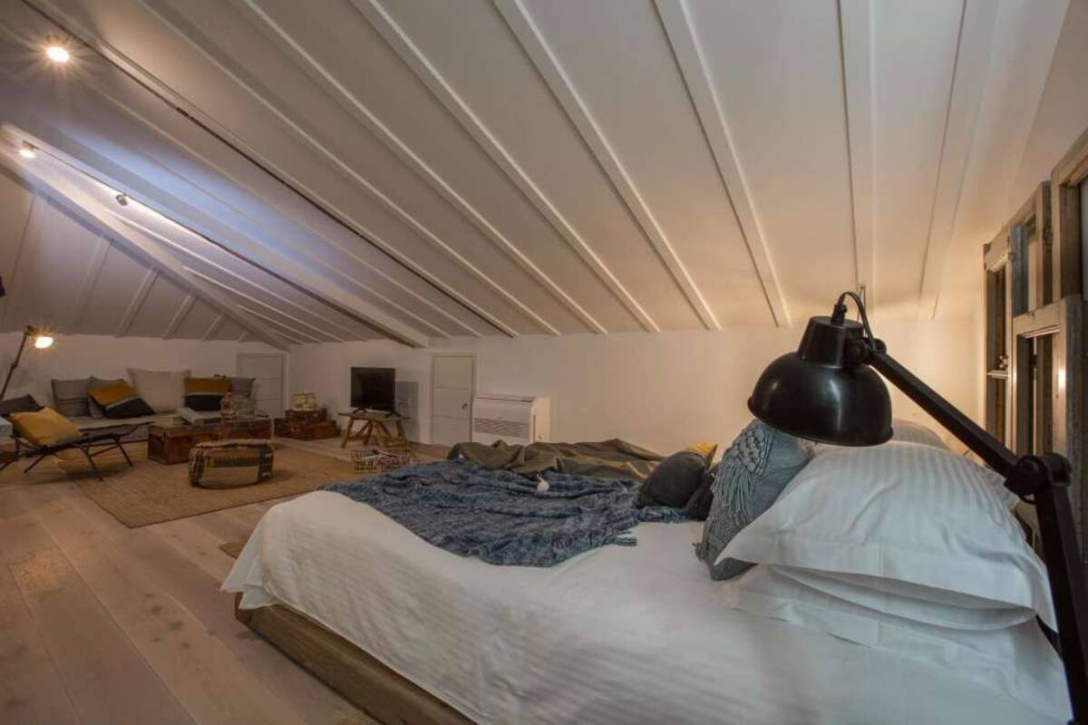 Une chambre avec un grand lit, un bureau et une chaise. Il y a une fenêtre donnant sur l’extérieur.