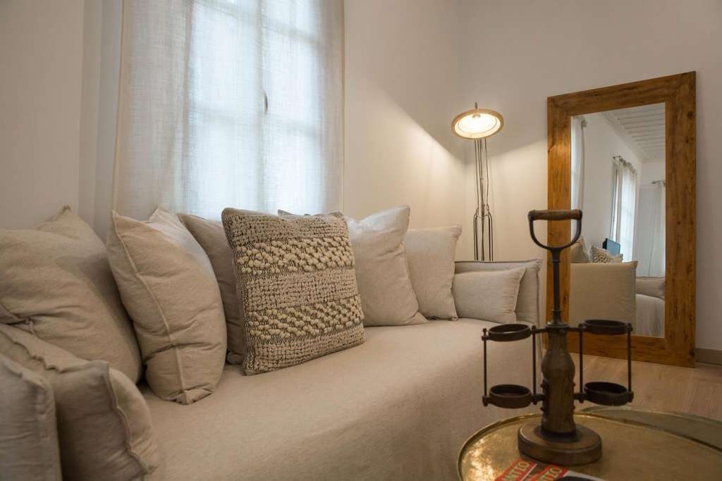 A cozy living room with a sofa, a floor lamp, and a mirror.