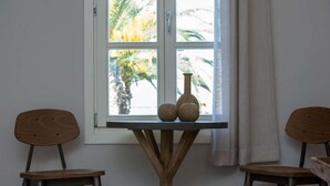 A room with a window, two wooden chairs, and a table with two vases. - Amymone Suites (Nafplio)