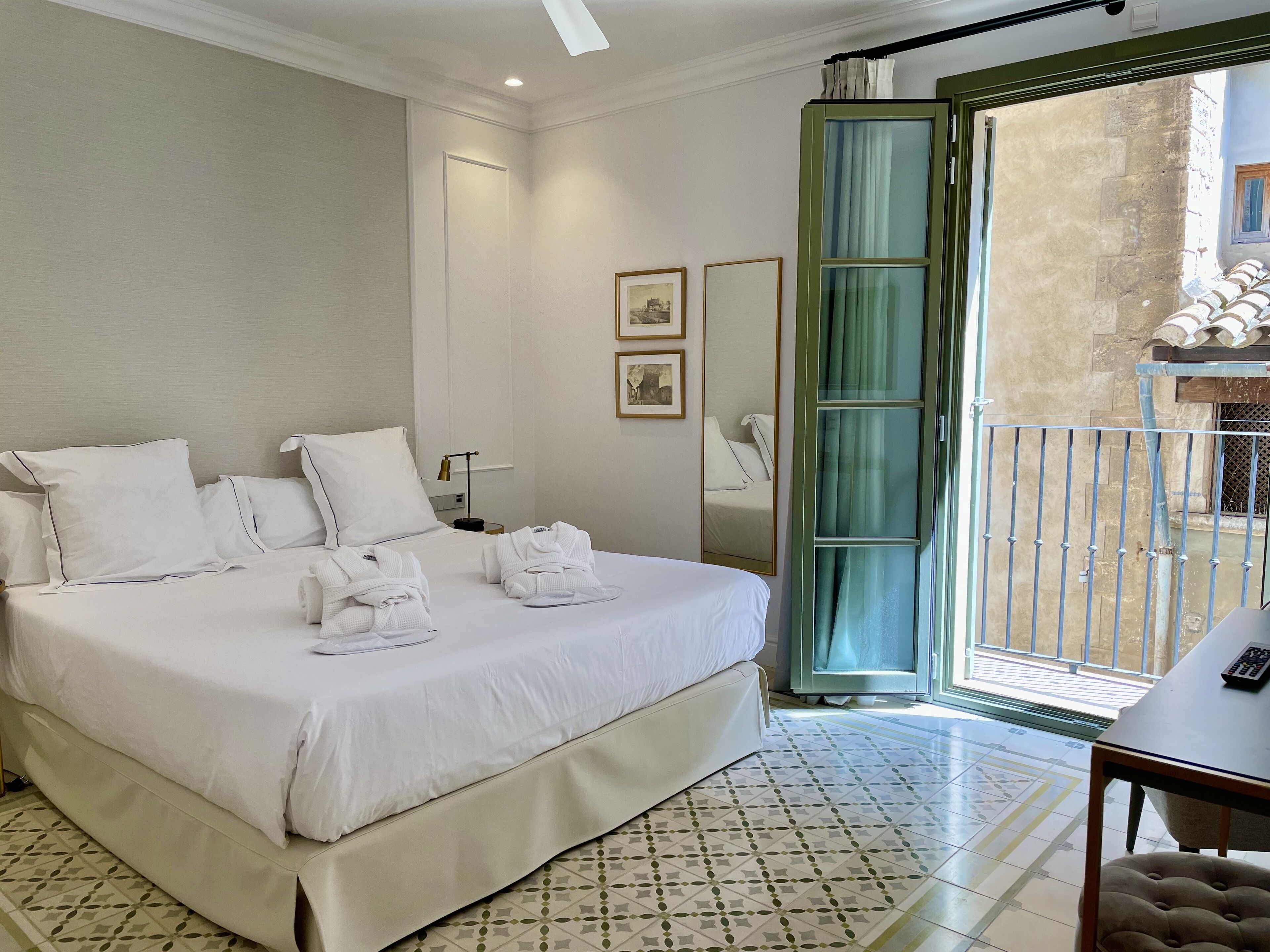 Ein Hotelzimmer mit einem großen Bett, einem Nachttisch, einem Spiegel und Blick auf den Balkon.