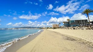 A beach with a clear sky, a sandy shore, and buildings in the background. - Hotel Basílica (Palma de Mallorca)