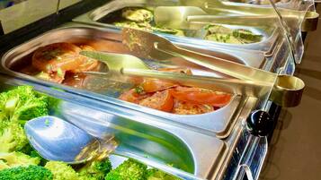 A buffet with various food options including broccoli, tomatoes, and other vegetables.